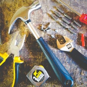 Collection of hand tools including hammer, screwdriver, and pliers in a workshop setting.