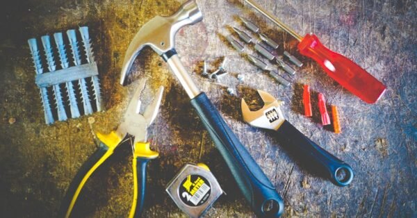 Collection of hand tools including hammer, screwdriver, and pliers in a workshop setting.